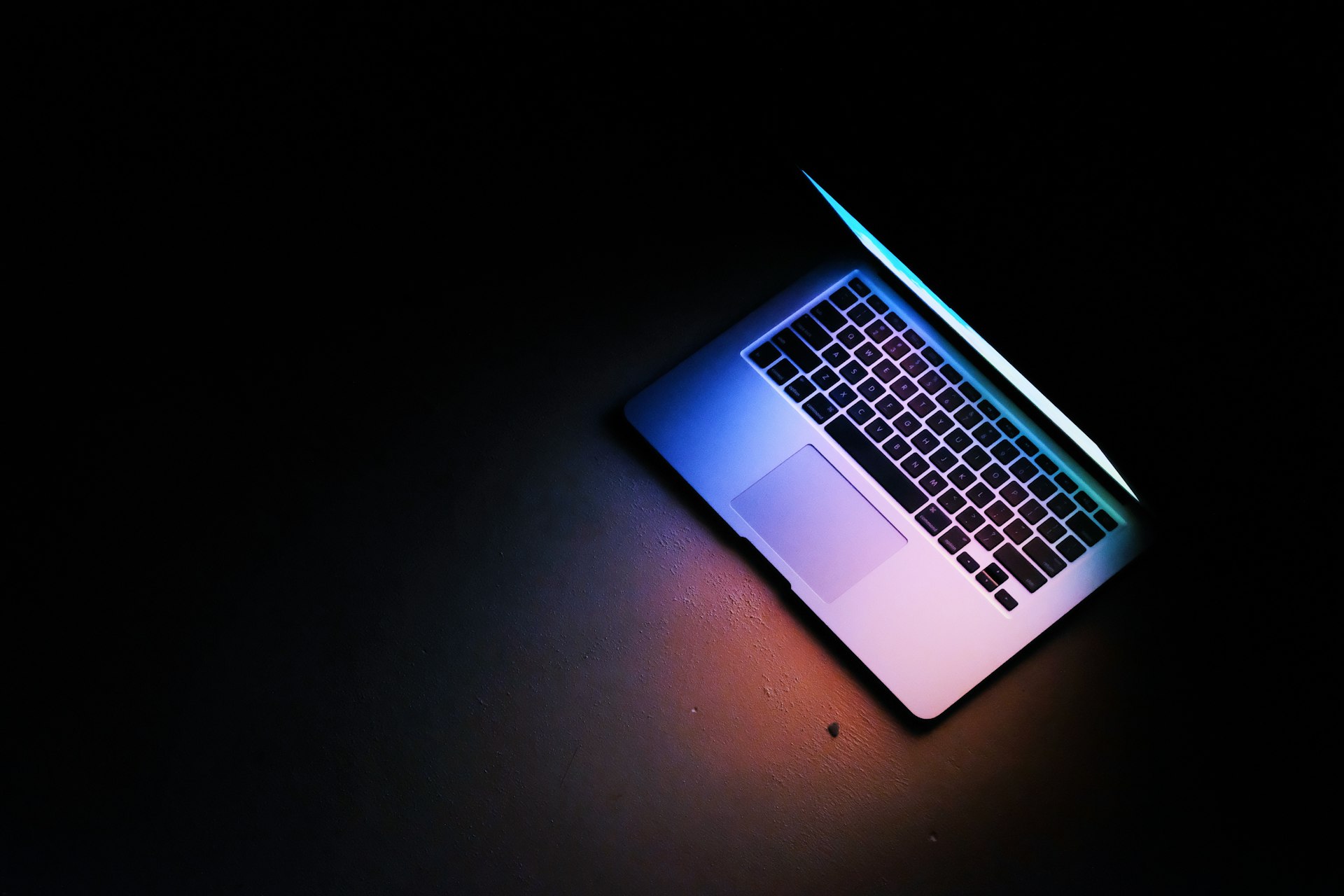 Ανοιχτό laptop με μπλε φωτισμό σε σκοτεινό γραφείο